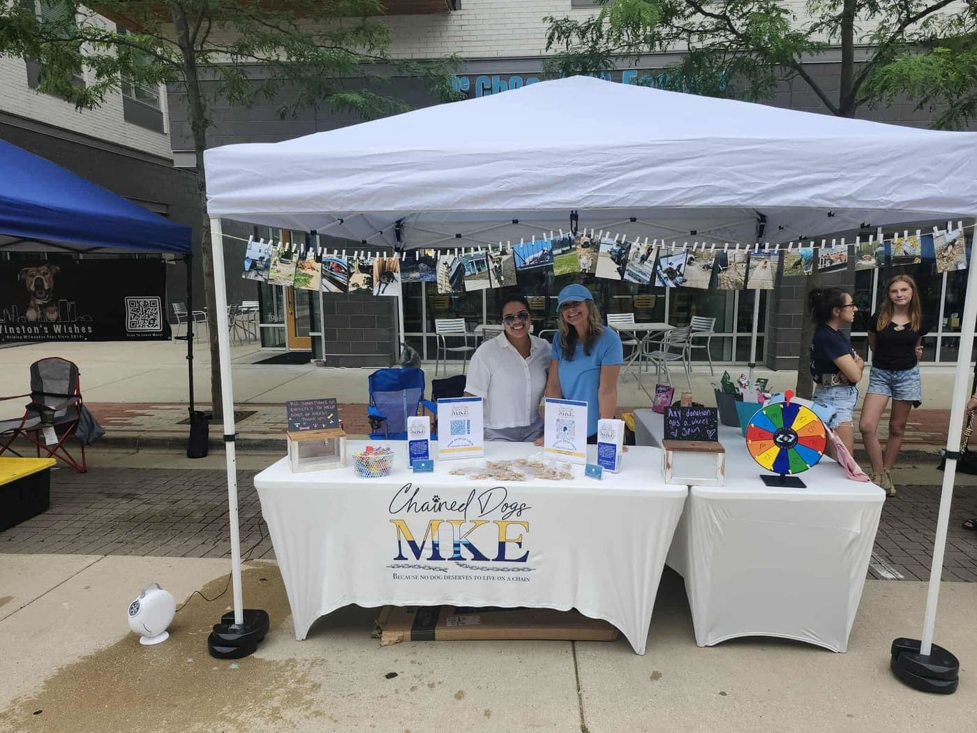 Two Chained Dogs MKE volunteers smiling at their event booth