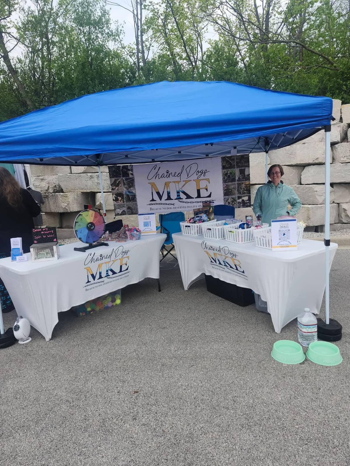 The Chained Dogs MKE booth tent with branded tables and a prize wheel at a Milwaukee event
